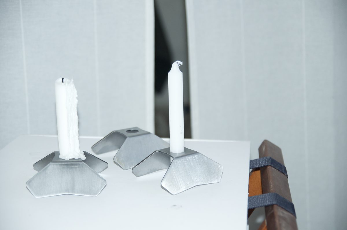 A pair of Tetrapod candle holders, one with a wax-covered candle, one with a fresh candle